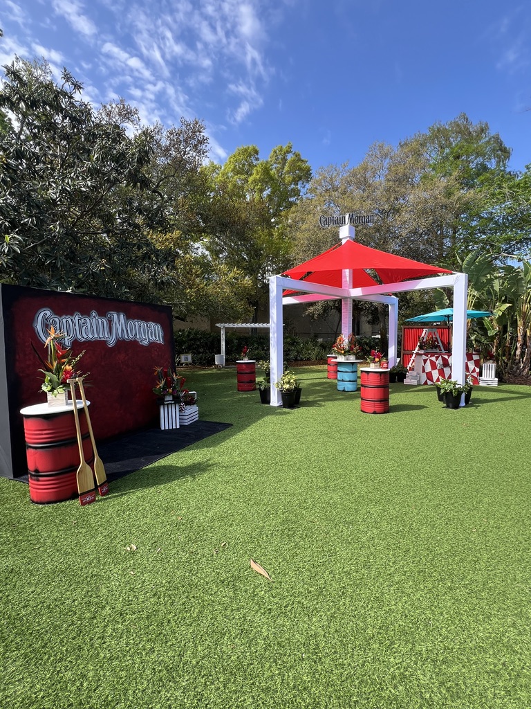 Vibrant Captain Morgan event space on Florida’s Gulf Coast, showcasing red and white themed canopies, decorative barrels, and tropical plants, set up by UDREAM EVENTS