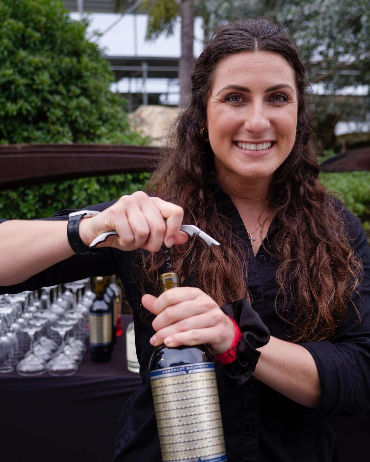 Smiling bartender opening a bottle of wine, preparing for a sophisticated gathering in St. Petersburg, Florida.