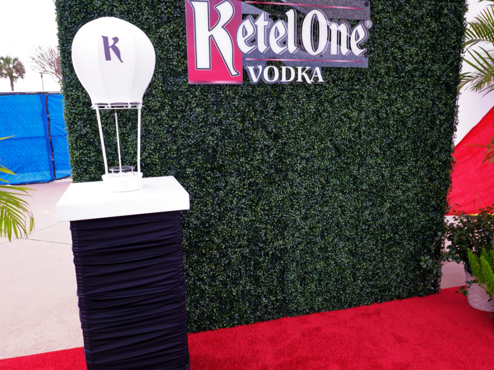 Ketel One Vodka branded display with green hedge backdrop and a decorative hot air balloon, styled by UDREAM EVENTS for an elegant event setup in the Tampa Bay area.