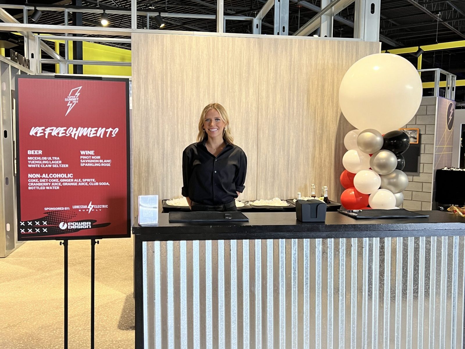 Sleek beverage stand with a cheerful bartender, offering refreshments at a modern corporate event space in Florida.